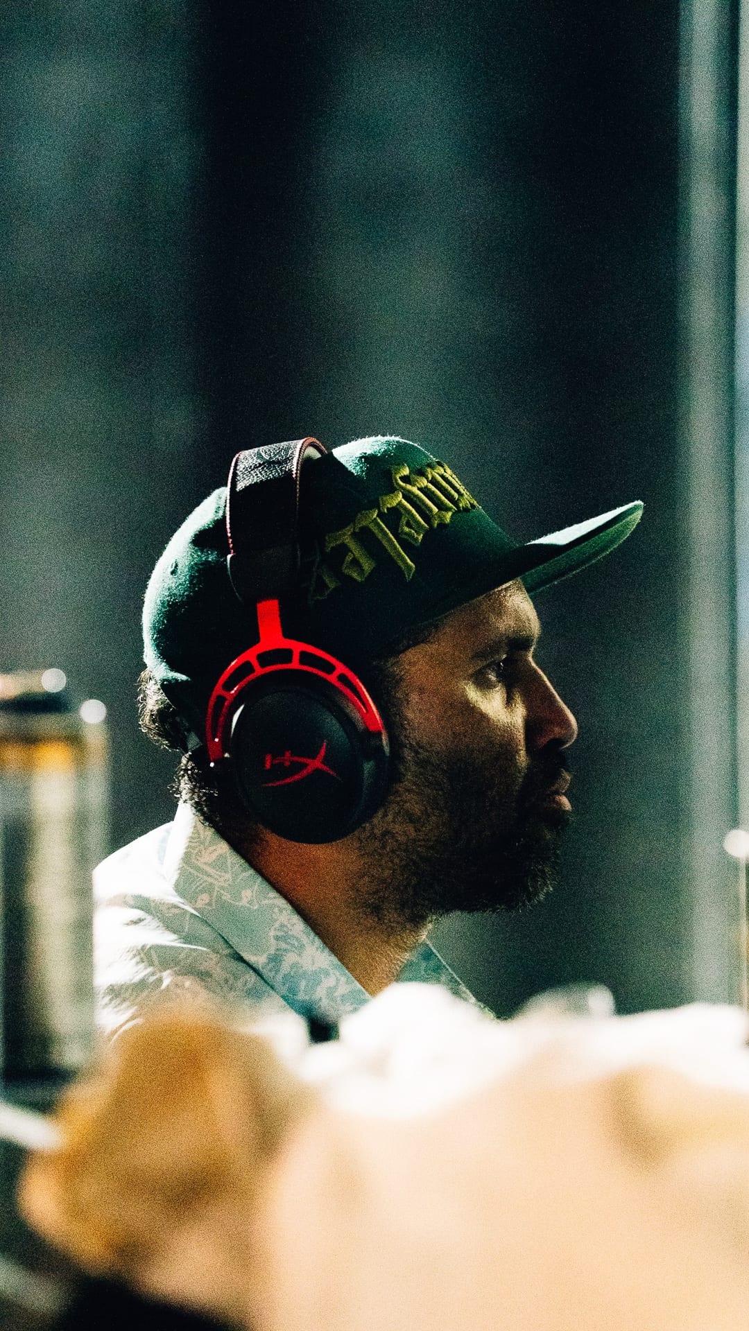 Retna in profile wearing headphones during the impromptu live art session