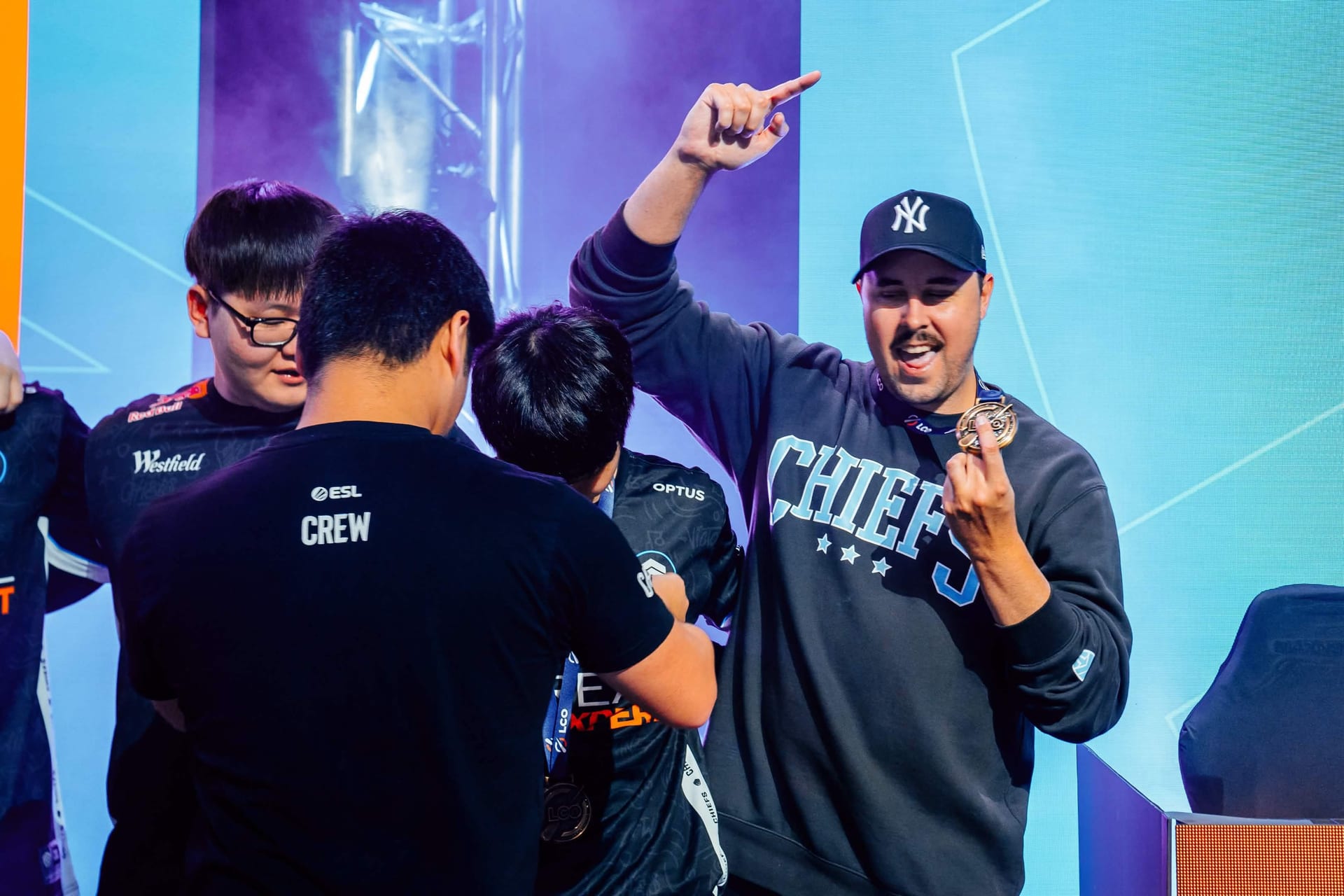 Chiefs Esports Club players celebrating on stage in their L'Oreal Men Expert and Optus jerseys at the LCO grand final