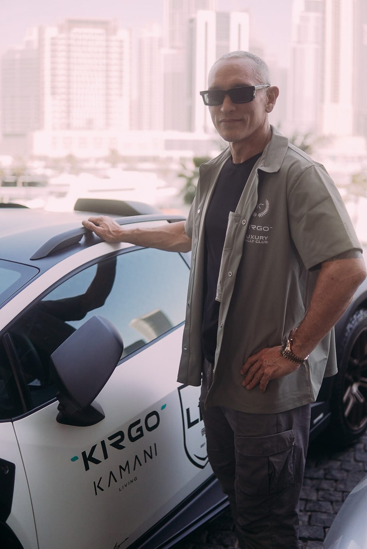 Rally guest beside a Kirgo and Kamani branded car against the Dubai skyline